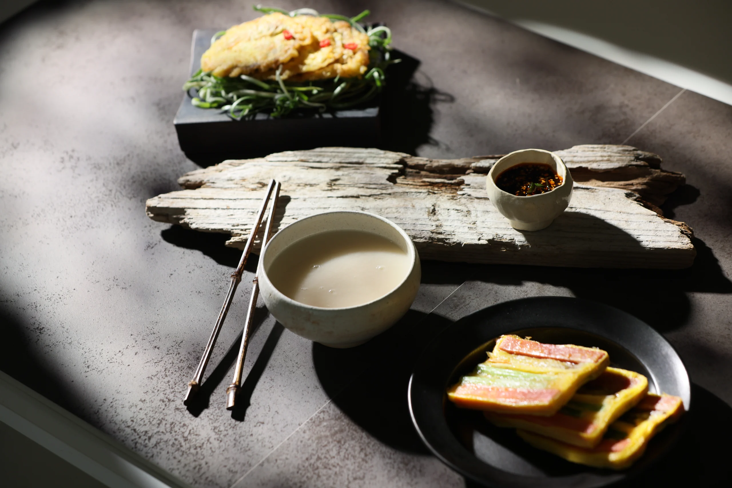 Makgeolli served in a ceramic bowl alongside Korean food