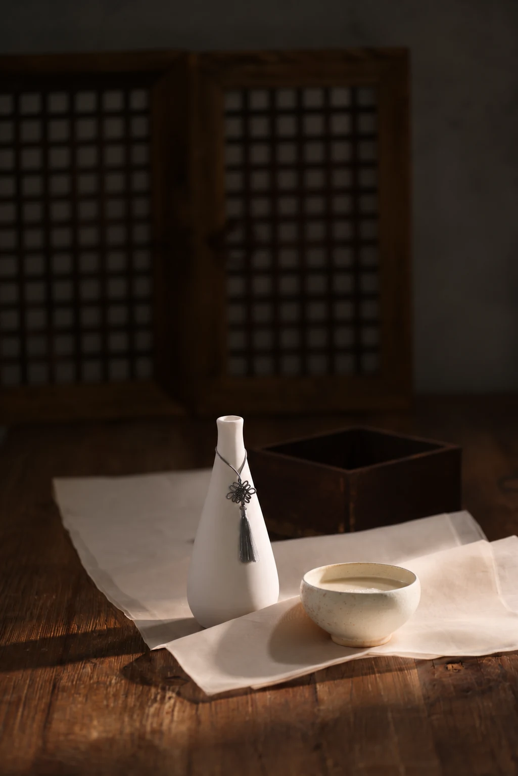 A ceramic vessel and bowl of makgeolli in a traditional Korean setting